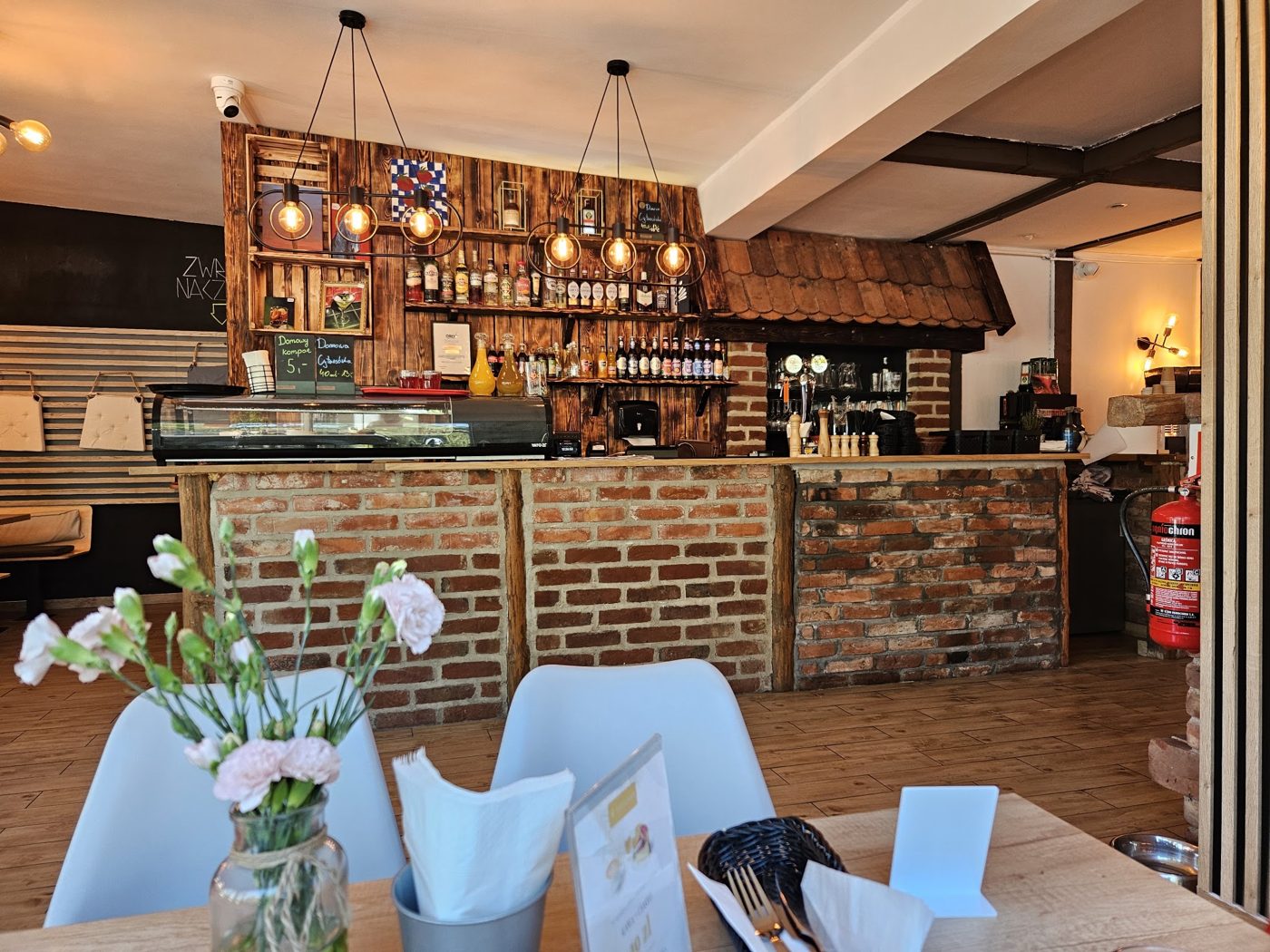 Wnętrze Baru Leśnego — ceglany bar, drewniane półki, żarówki